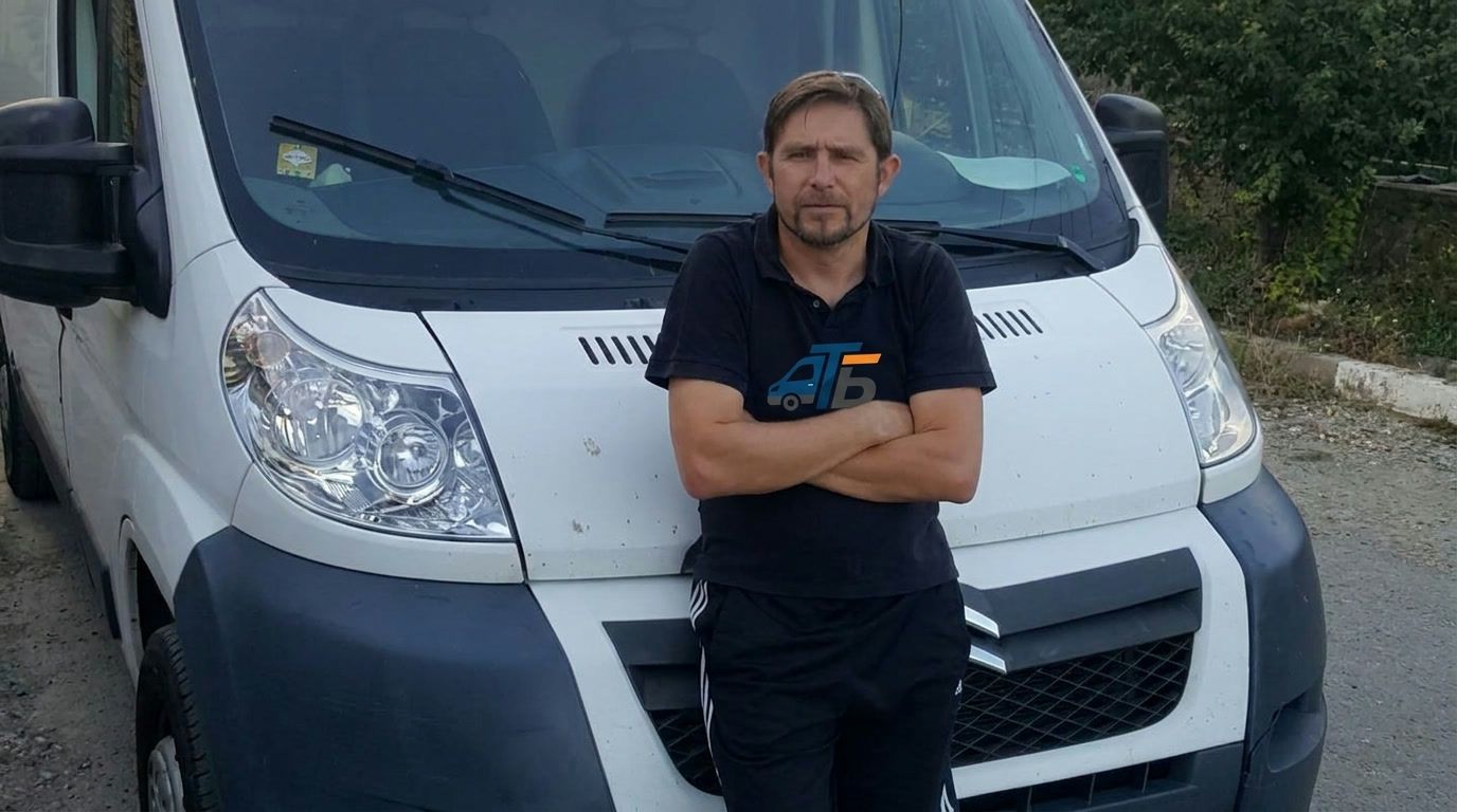 Невен Петков пред бус на фирмата, с работна тениска с логото